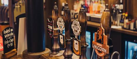 A bar area with multiple beer taps, a wooden counter, and a red sign with 'HELLES' on it.