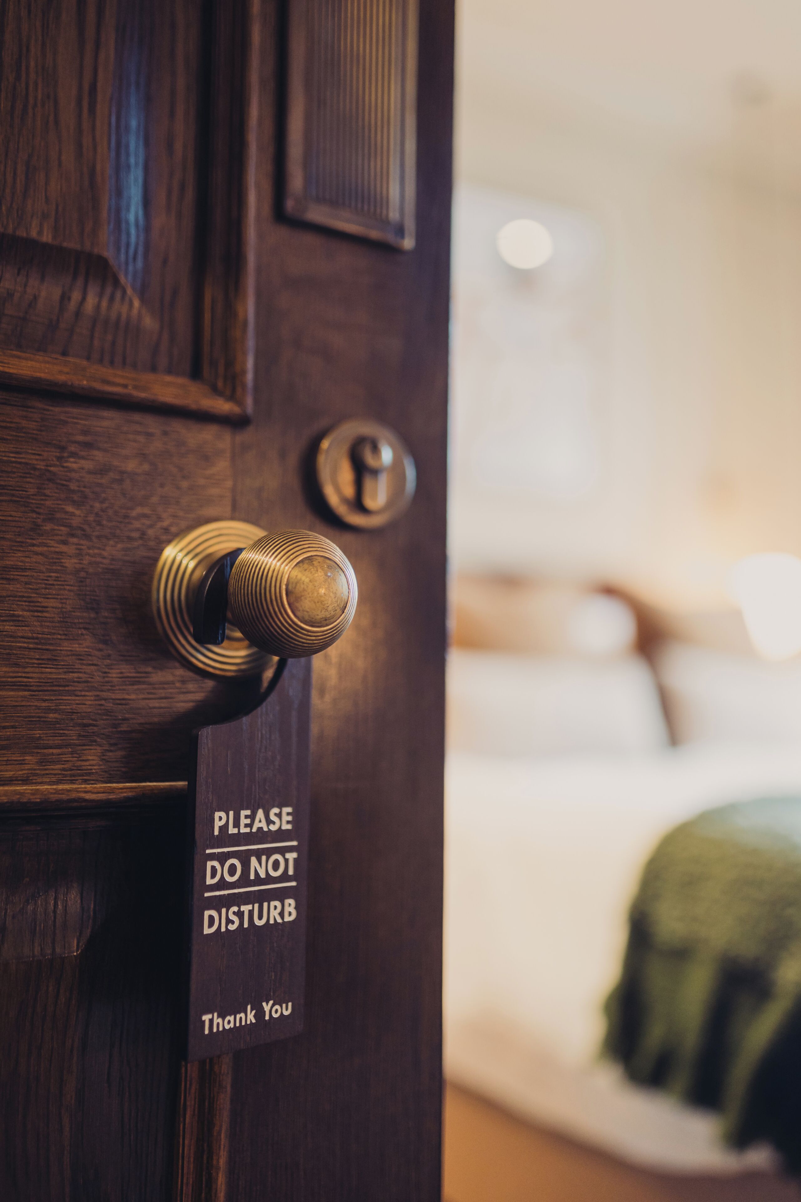 A wooden door with a brass doorknob and a sign that reads 'PLEASE DO NOT DISTURB Thank You.'