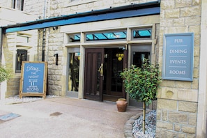 A stone building with a sign indicating pub dining events and rooms.