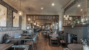 A restaurant with wooden flooring, high tables, and cushioned seating. - The Wheatley Arms (Ilkley)