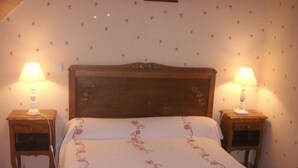 A bedroom with a wooden headboard, two bedside tables with lamps, and floral-patterned bedding. - Charming cottage near the Sioule River with private garden (Saint-Germain-de-Salles)
