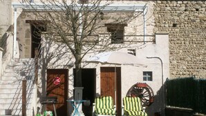 A rustic building with a stone wall, a wooden door, and a small table with chairs outside. - Charming cottage near the Sioule River with private garden (Saint-Germain-de-Salles)