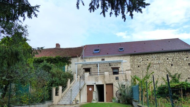 A stone building with a red-tiled roof, a small staircase leading to a door, and a fenced garden area. - Charming cottage near the Sioule River with private garden (Saint-Germain-de-Salles)