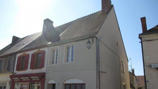Un bâtiment portant une enseigne indiquant « BOUCHER, CHARCUTERIE, TRAITEUR », ce qui signifie qu’il s’agit d’une boucherie.