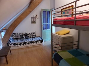 Une chambre de dortoir avec des lits superposés, un canapé-lit, un petit bureau et une fenêtre avec des rideaux.