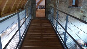 A wooden staircase with metal railings leading to a room with a stone wall and a window. - Charming Renovated Farmhouse - Pets Welcome - Near Commentry (Beaune-d'Allier)