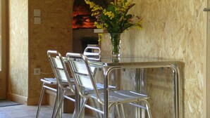 A dining area with a table and four chairs, a vase with flowers, and a brick fireplace in the background. - Cozy house with pool and sauna in nature (Vernusse)