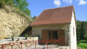 A stone building with a red-tiled roof, a wooden door, and a red metal fence. - Cozy house with pool and sauna in nature (Vernusse)