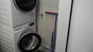 A laundry room with stacked washing machines and a drying rack.
