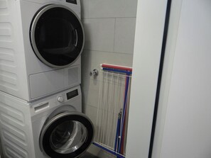 Een wasserette met gestapelde wasmachines en een droogrek.