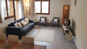 A living room with a sofa, chairs, a coffee table, and a TV stand.