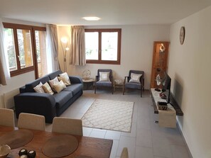 Een woonkamer met een bank, fauteuils, een salontafel en een tv-meubel.