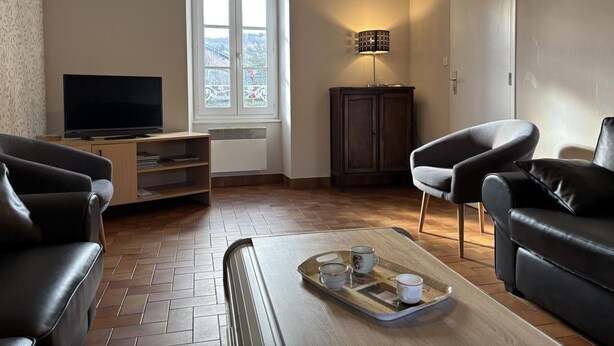 A living room with a flat-screen TV, two leather sofas, a wooden coffee table with a tray, a cabinet, and a window with a view. - Spacious lodging in La Guillermie, pets allowed, garden (La Guillermie)