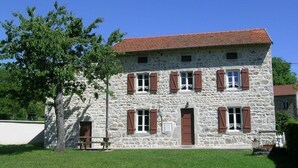 A two-story stone building with a red-tiled roof, multiple windows with shutters, and a grassy lawn. - Spacious lodging in La Guillermie, pets allowed, garden (La Guillermie)