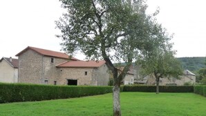 A stone building with a red roof, surrounded by a well-maintained lawn and hedges. - Spacious lodging in La Guillermie, pets allowed, garden (La Guillermie)
