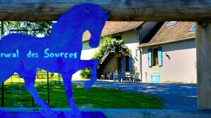 Une porte en bois rustique ornée d’une silhouette de cheval bleue et de l’inscription « rural des Sources ».