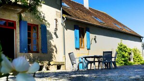 Une maison avec une allée en gravier, un espace salon extérieur et un jardin.