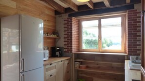Una cocina compacta con refrigerador, cafetera y ventana con vista a follaje.