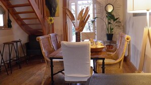 Un comedor con sillas de mimbre, una mesa de madera y un florero con flores secas.