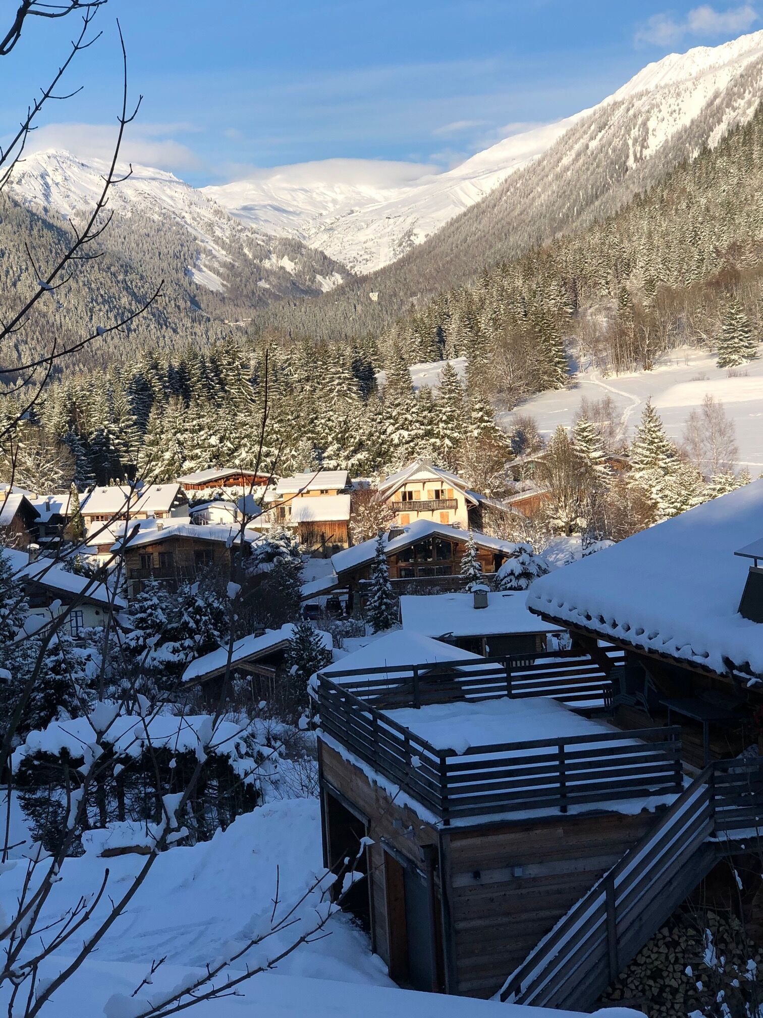 Ein verschneites Bergdorf mit rustikalen Holzhäusern und freiem Blick auf die umliegenden Berge.