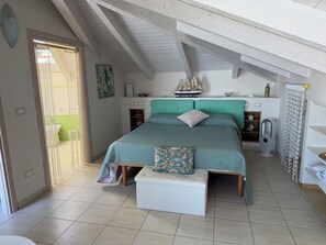 A bedroom with a bed, bedside tables, a ship model, and a window with curtains.