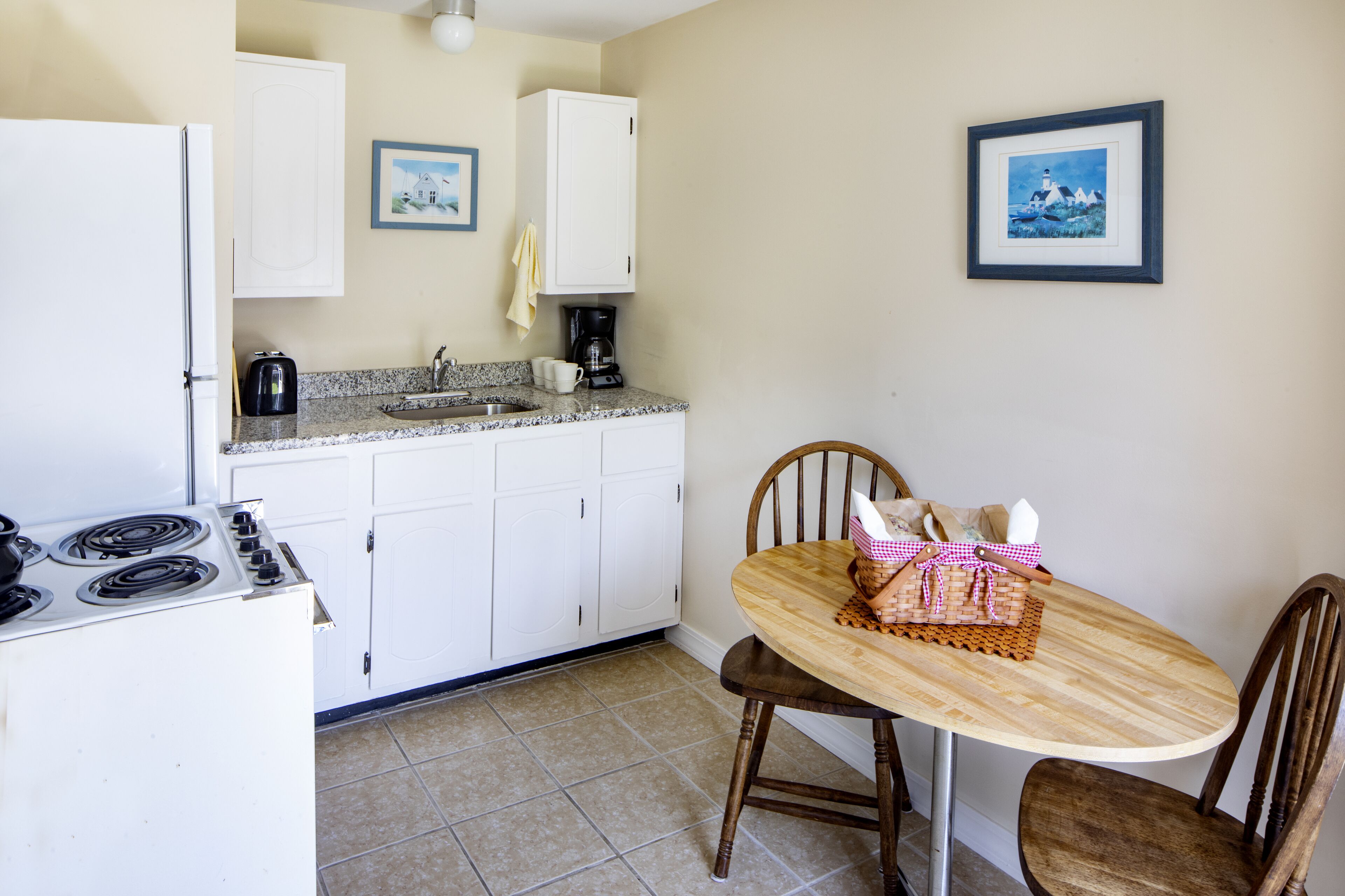 A kitchen with white cabinets, a stove, a sink, and a dining table with chairs.
