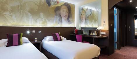 Habitación de hotel con dos camas, un escritorio, una lámpara y un mural grande en la pared.