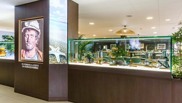 A reception area with a glass display case containing various items, a poster on the wall, and a ceiling light fixture. - roi soleil prestige (Saint-Avold)
