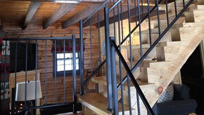 A wooden cabin interior with a staircase, a welcome sign, and a fireplace.