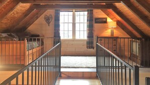 An attic room with wooden beams, a window with a heart decoration, and a sign that reads "ADVENTURE".
