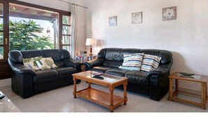 A living room with two black leather sofas, a wooden coffee table, and a small wooden side table. - Villa Las Palmeras in Playa Blanca (Playa Blanca)