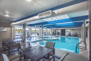 Un espace piscine comprenant un jacuzzi, des chaises longues et une table avec des chaises.