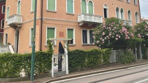 Un immeuble à plusieurs étages avec des volets verts, un balcon et un portail.