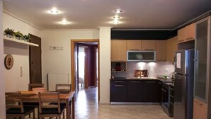 A modern kitchen with dark cabinets, a stainless steel refrigerator, and a microwave. There is a dining area with a wooden table and chairs. - Thisio Modern House (Athens)