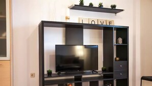 A modern entertainment unit with a flat-screen TV, shelves for books and decorative items, and a shelf with plants and a sign that says "LOVE". - Thisio Modern House (Athens)