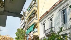 A narrow street with buildings on either side, a red scooter parked on the left, and a tree in the center. - Thisio Modern House (Athens)