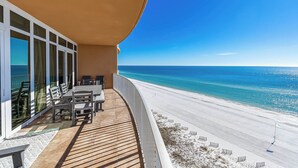Un balcone con pavimento in legno, un tavolo con sedie e vista sulla spiaggia e sull'oceano.