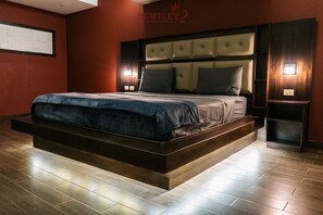 A spacious bedroom with a large bed, a wooden headboard, and a red accent wall.