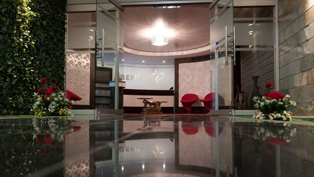 A modern reception area with a glass floor, a reception desk, and red chairs.
