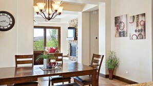 A dining area with a wooden table, chairs, a chandelier, and artwork on the walls. - Golf Views on the Ridge GOLF VIEWS!! 2 Community Pools! (Washington)