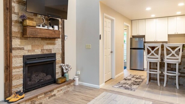 A modern kitchen with white cabinets, a stainless steel refrigerator, and two white chairs.