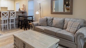 A living room with a sofa, coffee table, and a dining area with chairs and a table.