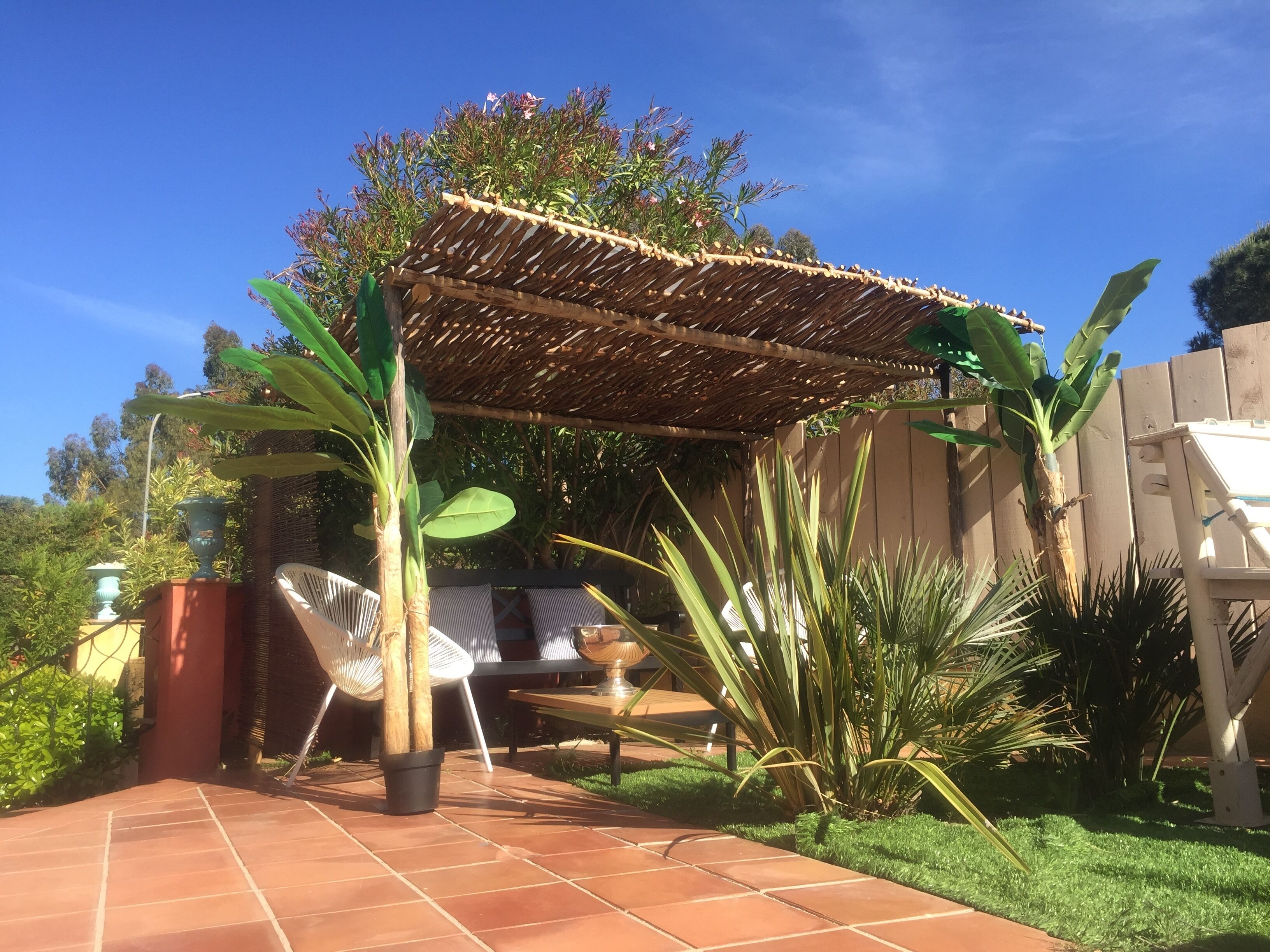 Un'area patio con una pergola, mobili da esterno e diverse piante.