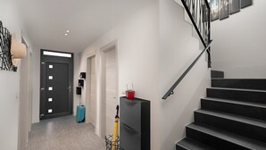 A modern interior with a staircase, a hallway leading to a door, and a potted plant on a shelf. - Beautiful Villa Linea near the sea with private pool! (Fazana)