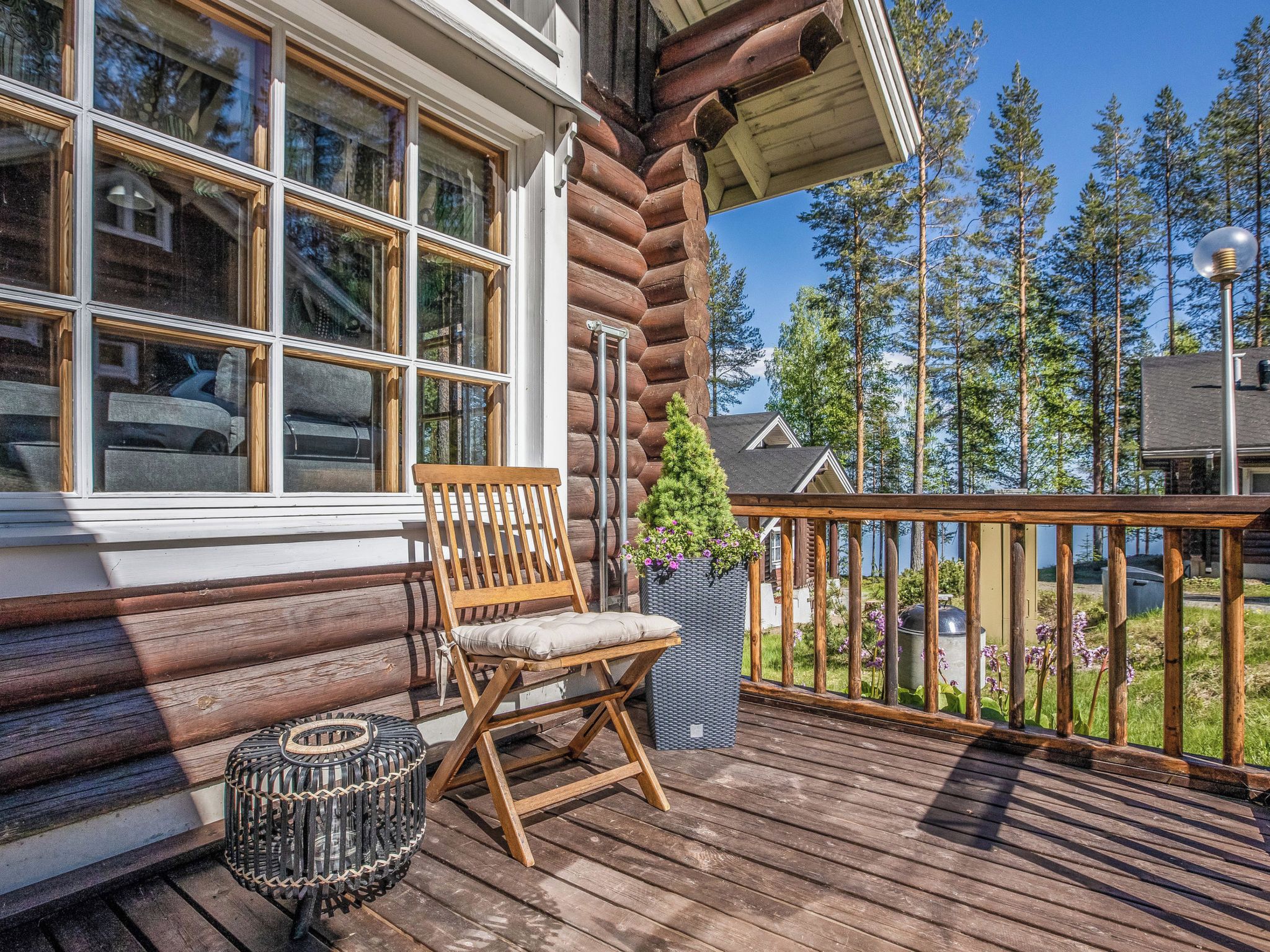 Une terrasse en bois avec une chaise en bois et un panier en osier.