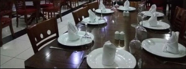 A dining area with tables set for service, chairs, and a tiled floor.