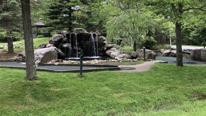 Ein Park mit einem Wasserfall, großen Felsen und einem Gazebo.