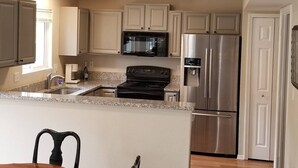A kitchen with a granite countertop, stainless steel appliances, and beige cabinetry. - 4 Bedroom Mountain Retreat - Garden of the Gods (Colorado Springs)
