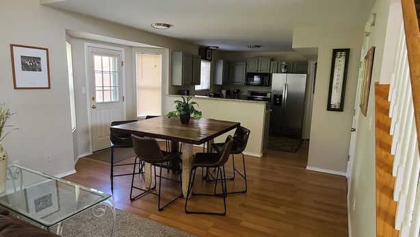 A modern kitchen with stainless steel appliances, a dining area with a wooden table and chairs, and a glass coffee table. - 4 Bedroom Mountain Retreat - Garden of the Gods (Colorado Springs)