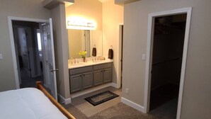 A bedroom with a bed, a walk-in closet, and a bathroom with a vanity and mirror. - 4 Bedroom Mountain Retreat - Garden of the Gods (Colorado Springs)